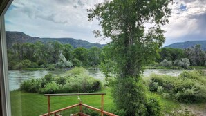 A deck with a view of a river and surrounding greenery.
