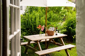 Enjoy a casual dining experience in our serene garden setting, complete with a picnic table, wicker basket, and wine.