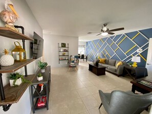 Relax in this inviting living room with a ceiling fan, comfortable sofa, and decorative shelves.