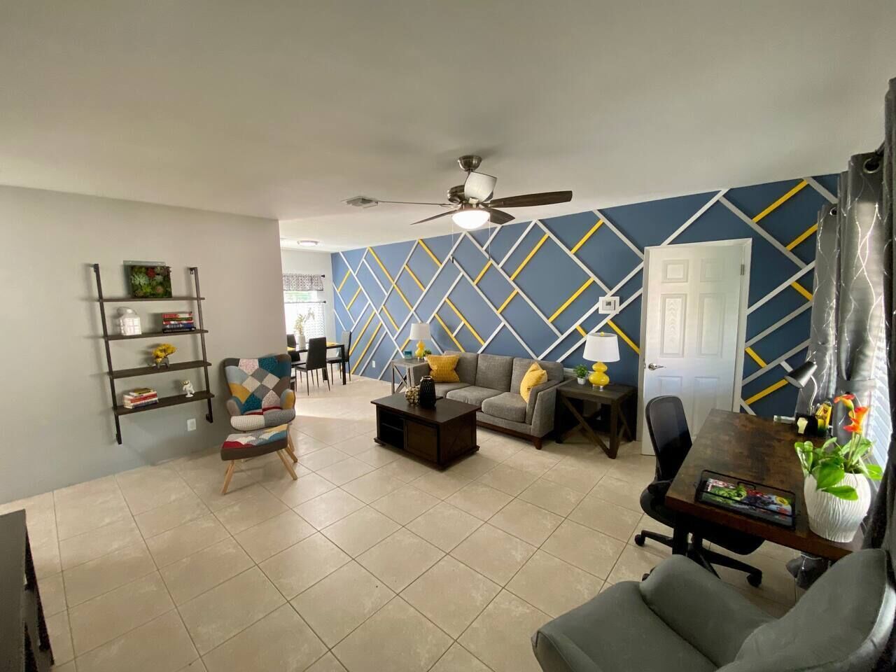 A spacious living room with a sofa, armchair, coffee table, and a bookshelf.