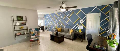 A spacious living room with a sofa, armchair, coffee table, and a bookshelf.