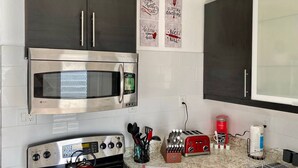 A kitchen with a stainless steel microwave, oven, and toaster. There are wall-mounted cabinets and a countertop with various kitchen items.