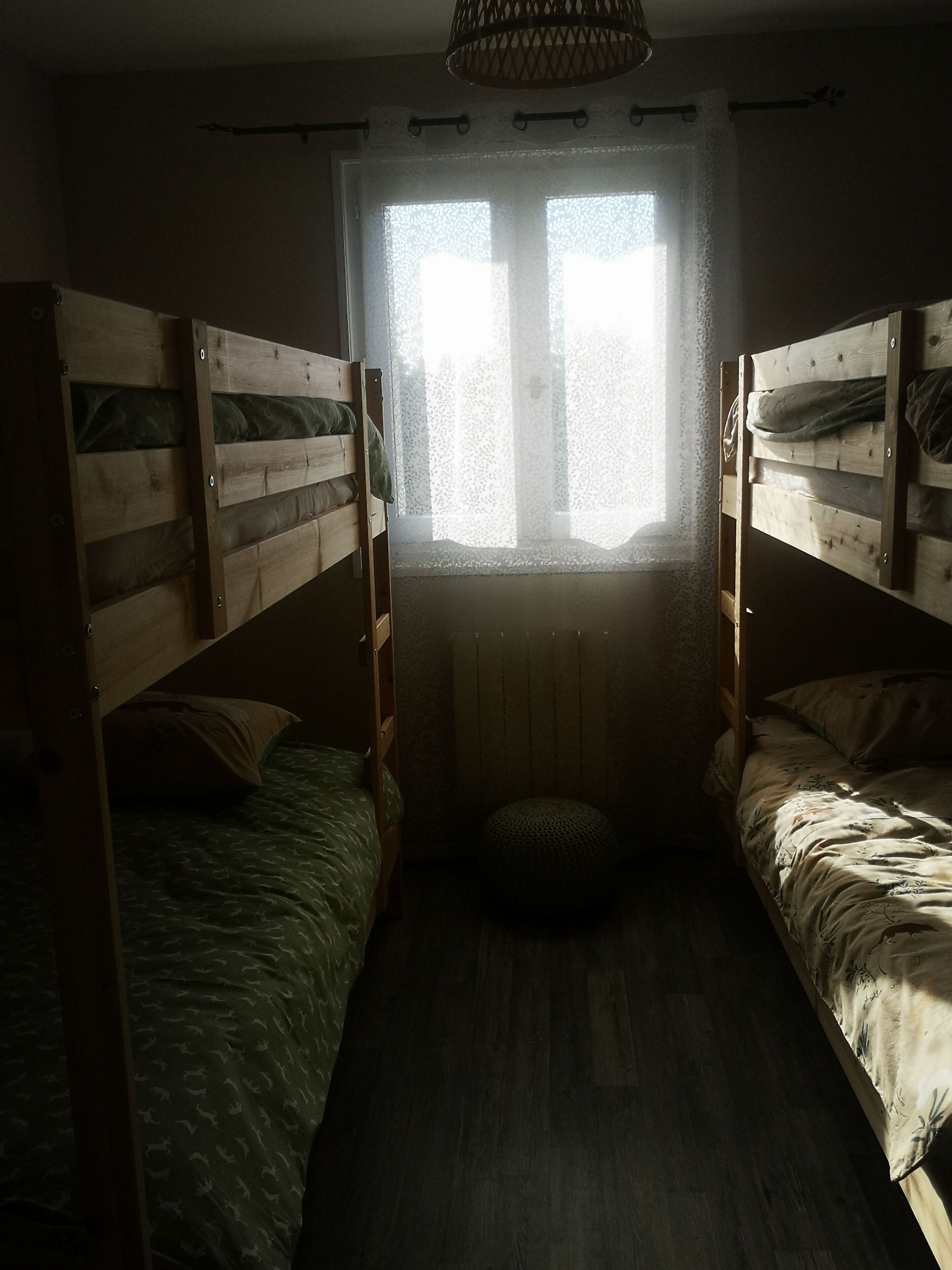 A room with two bunk beds, a window with lace curtains, and a radiator below.