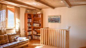 A cozy living room with a leather sofa, a wooden bookshelf, and a painting on the wall. - Gorgeous home in åryd with kitchen (Åryd)