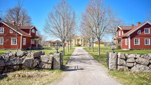 A pathway leading to a row of traditional red wooden houses with stone walls on either side. - Gorgeous home in åryd with kitchen (Åryd)