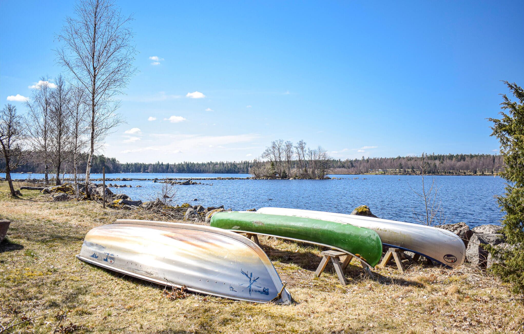 Two canoes resting on wooden stands by a lake with a forested shoreline.