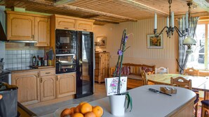 A kitchen with wooden cabinets, a black refrigerator, and a dining area with a table and chairs. - Gorgeous home in åryd with kitchen (Åryd)