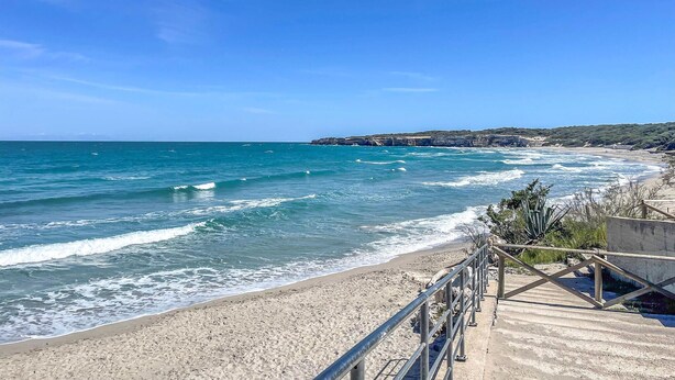 Une plage côtière avec une promenade en bois qui mène au bord de l’eau.