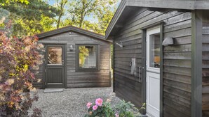 Une cabane en bois avec un petit porche, une porte et une fenêtre.
