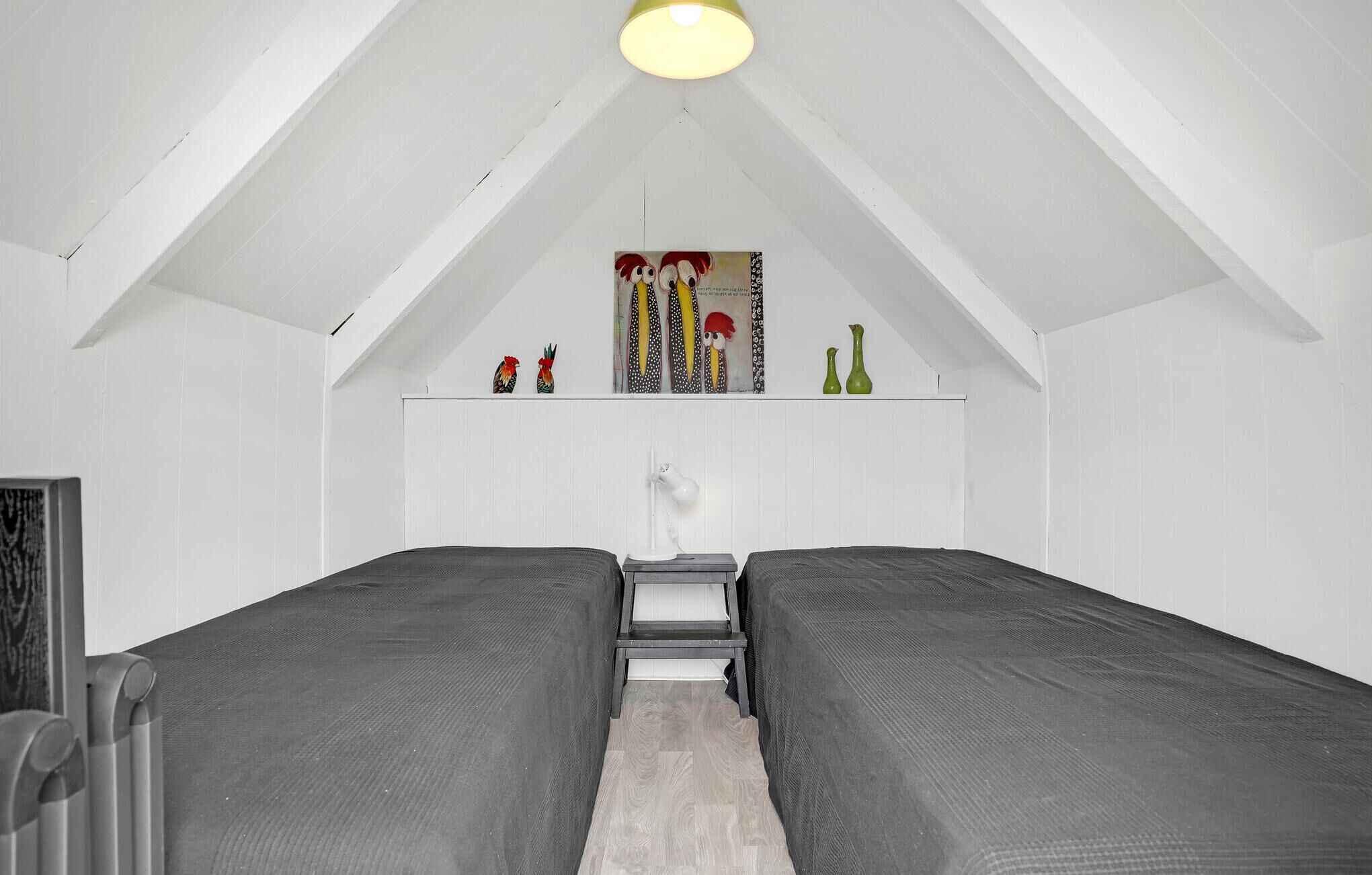 Een kamer met twee bedden, een wit plafond en een plank met decoratieve spullen.