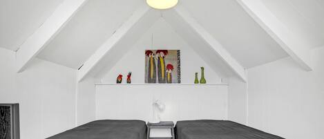 Een kamer met twee bedden, een wit plafond en een plank met decoratieve spullen.