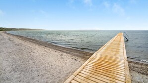 Eine hölzerne Pier, die sich in ruhiges Wasser erstreckt, mit einem klaren Himmel darüber.