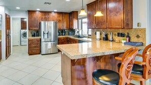 Eine moderne Küche mit Holzschränken, Edelstahlgeräten und einer Granitarbeitsplatte.