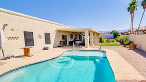 Ein Pool mit geschwungener Kante, eine überdachte Terrasse und Blick auf ein Gebirge.