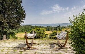 Deux hamacs sur une terrasse en pierre, avec vue sur un paysage montagneux.