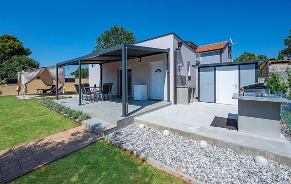 Una casa moderna con un porche cubierto, un garaje y un pequeño jardín.