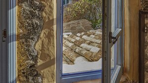 A stone wall with a window revealing a stone pathway and greenery outside. - Casa Azul  at Masia Nur Sitges (Adults only 18+) (Canyelles)
