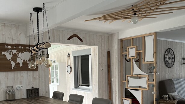 Una cocina moderna con una isla de madera, armarios blancos y una lámpara colgante.