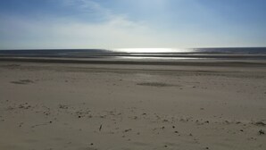 Una playa con una extensa zona arenosa y cielo despejado.