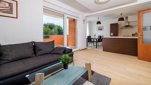 A modern living room with a sofa, a glass coffee table, and a view of the outdoors. - 3 bedroom beach front apartment in Opric (Opric)