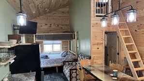 A cozy cabin-style room with a bunk bed, a dining table with chairs, and a ladder to the upper bunk. -  Modern Cabin to relax and unwind  (Au train)