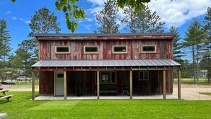 A rustic wooden building with a metal roof, a porch, and a small front yard. -  Modern Cabin to relax and unwind  (Au train)