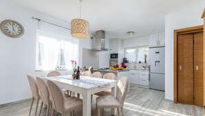 A modern kitchen with a dining area, featuring a marble table, beige chairs, and a pendant light. - Awesome home in Stinjan (Stinjan)