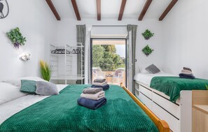 A modern bedroom with two beds, a balcony, and a view of greenery. - Awesome home in Stinjan (Stinjan)