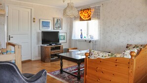 Un salon chaleureux avec un canapé en bois, un téléviseur et une table à manger.