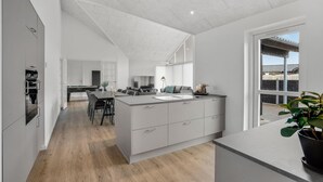 Cozinha moderna com ilha central, área de refeições com mesa de bilhar e uma grande janela com vista para o exterior.