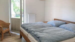 Ein Schlafzimmer mit Bett, Stuhl, Heizkörper und Fenster mit Jalousien.
