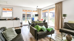 Ett modernt vardagsrum med en soffa, ett soffbord i glas och en matplats med ett bord och stolar.