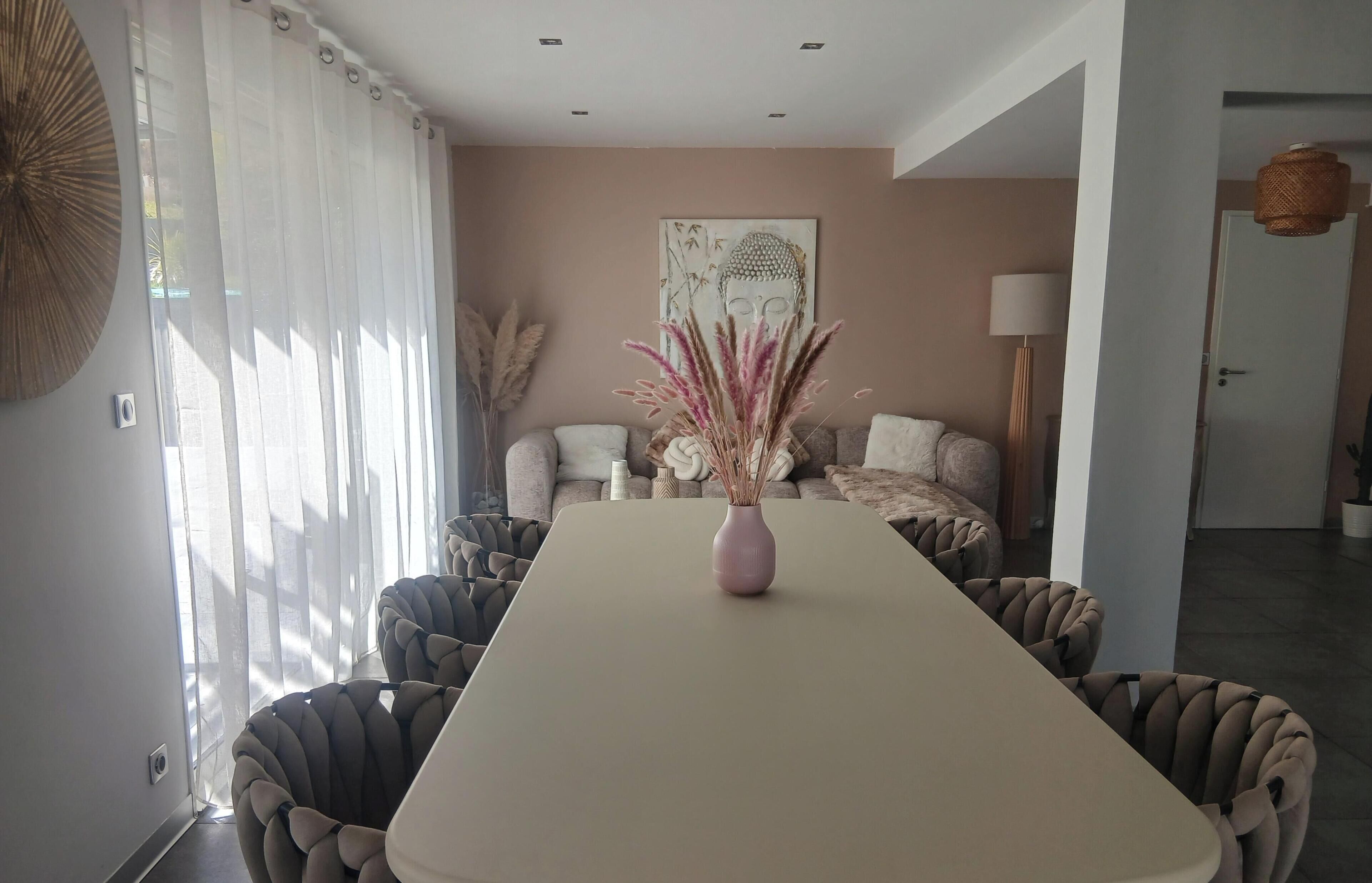 Ein modernes Wohnzimmer mit Esstisch, Sofas und einer Buddha-Statue an der Wand.