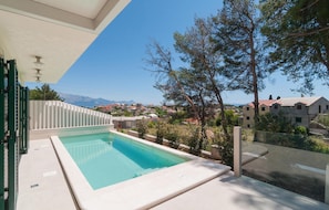 A swimming pool with a view of a residential area and mountains in the background.