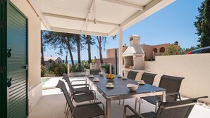 An outdoor patio with a table and chairs, a bowl of fruit, and a view of the sea and buildings in the background. - Cozy home in Sumartin (Sumartin)