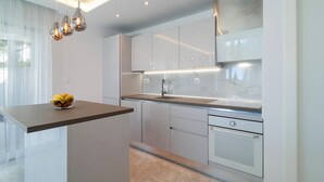 A modern kitchen with a marble backsplash, stainless steel appliances, and pendant lighting. - Cozy home in Sumartin (Sumartin)