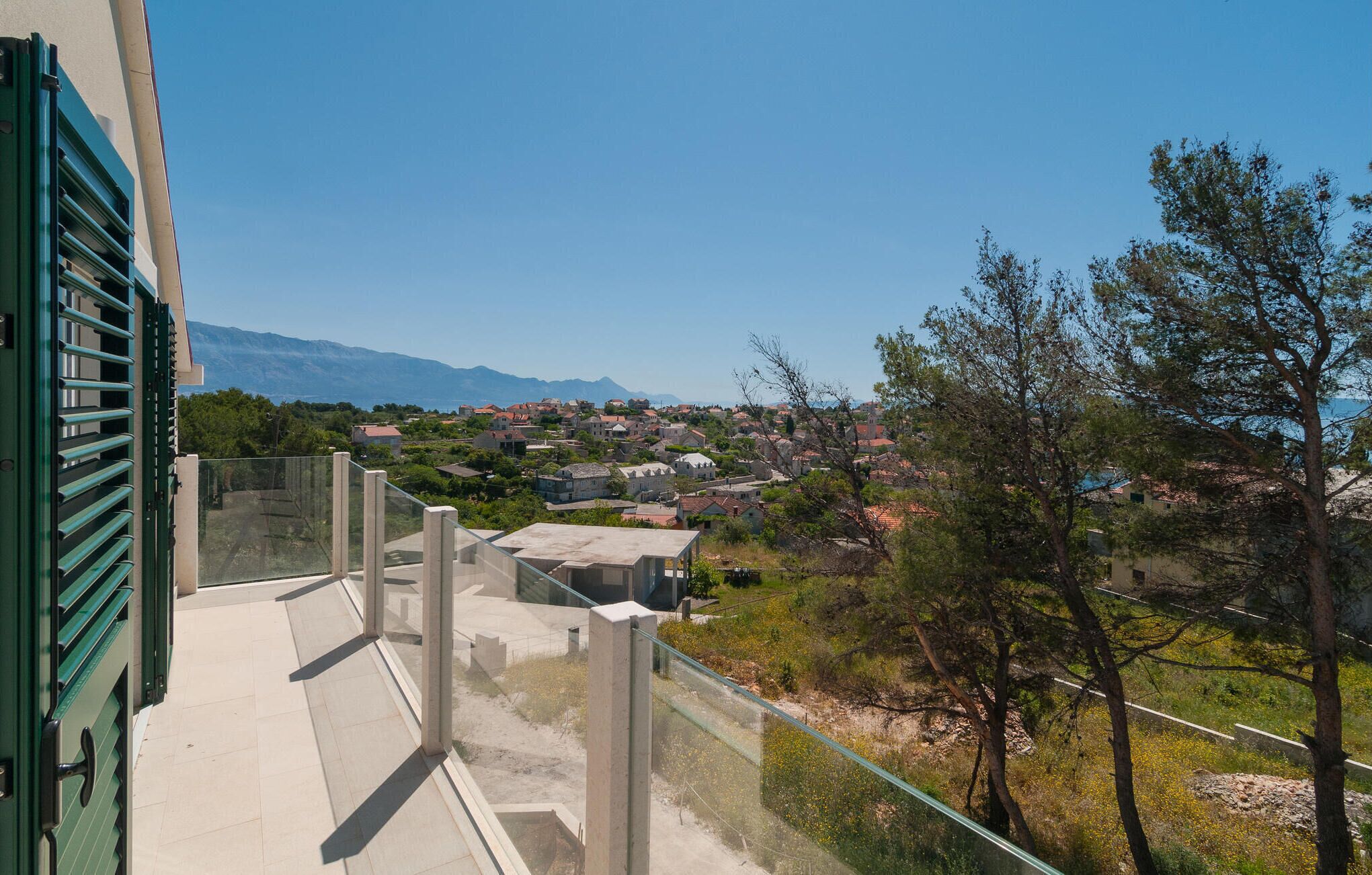 A balcony with a clear view of a coastal town and mountains in the distance.