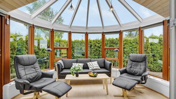 A conservatory with a glass ceiling, a black leather sofa, two leather armchairs, a wooden coffee table, and a bowl of fruit. - Stunning home in Haderslev with WiFi (Haderslev)