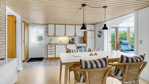 A modern kitchen with white cabinets, a dining area with wicker chairs, and a large window offering a view of greenery. - Stunning home in Haderslev with WiFi (Haderslev)