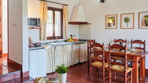 A kitchen with a dining area, a microwave, a sink, and a dining table set for four. - Lovely home in Estepa with house a panoramic view (Estepa)