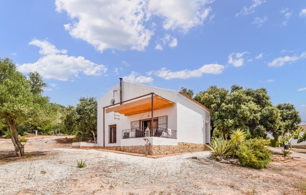 Un bâtiment blanc doté d’un patio couvert et d’une base en pierre.