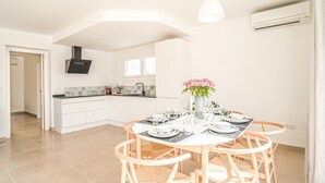 A modern kitchen with white cabinetry, a central island, and a dining area with a round table and wicker chairs. - Gorgeous home in Marbella (Marbella)