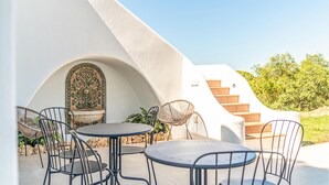 A modern outdoor patio with round tables and metal chairs, a decorative archway, and a staircase leading to a higher level. - Gorgeous home in Marbella (Marbella)