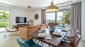 A modern living room with a dining area, large windows, and a view of the outdoors. - Stunning home in Sumartin (Sumartin)