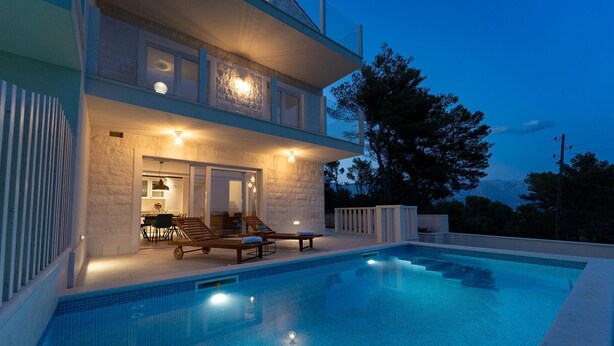 A modern two-story house with a swimming pool, outdoor seating, and a stone facade. - Stunning home in Sumartin (Sumartin)