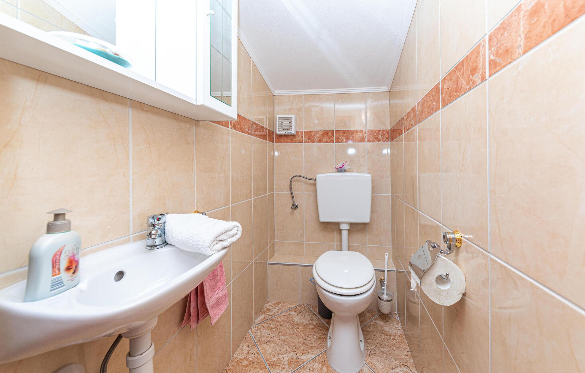 A compact bathroom with a sink, toilet, and shower.