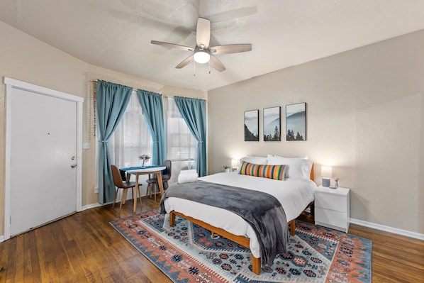 A bedroom with a bed, nightstands, a desk, and a chair.