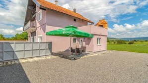 Un bâtiment à deux étages, doté d’un toit recouvert de tuiles rouges, d’un balcon et d’un parasol vert.