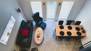 Ein modernes Interieur mit einem schwarzen Ledersofa, einem Holztisch und einem Esstisch mit Stühlen.