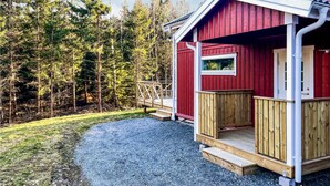 Eine rote Holzhütte mit einer Holzdielenveranda und einem kleinen Fenster.